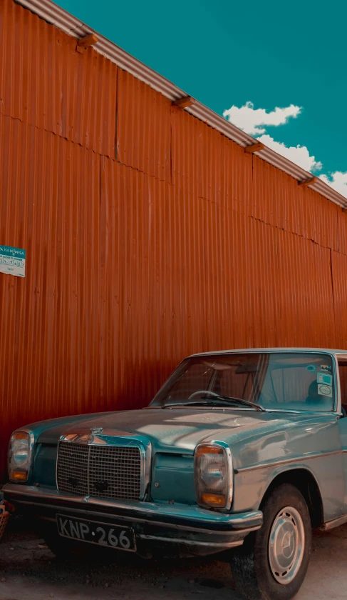 a small blue car parked next to a rusted building