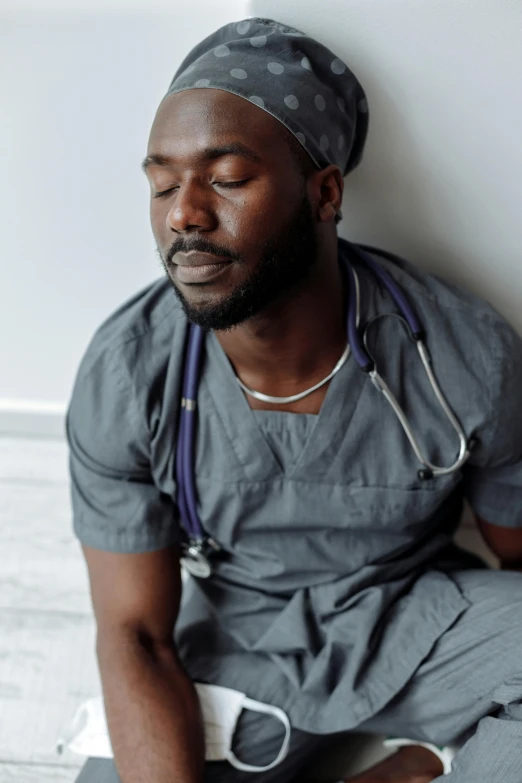 a man in scrubs sits down in his hospital uniform