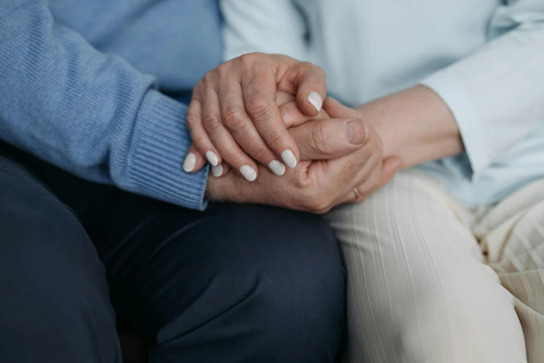 hands folded in the center of two people with blue sweaters