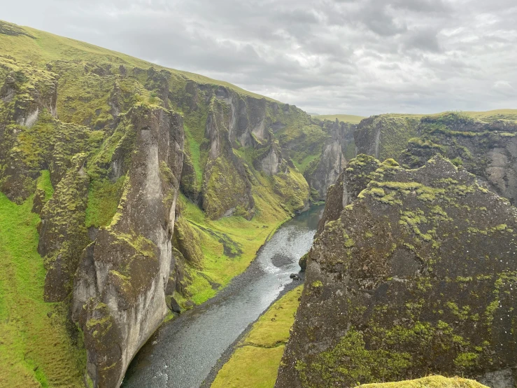 a river running between tall green rocky mountains