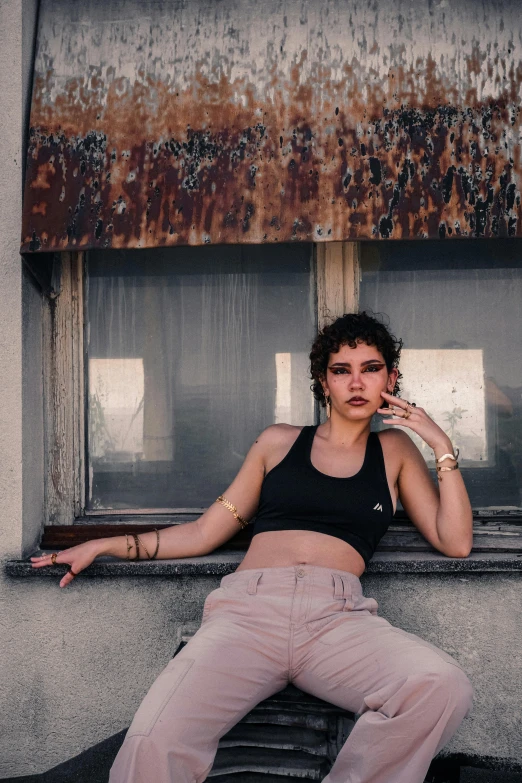 a young woman smoking a cigarette as she rests in the windowsill