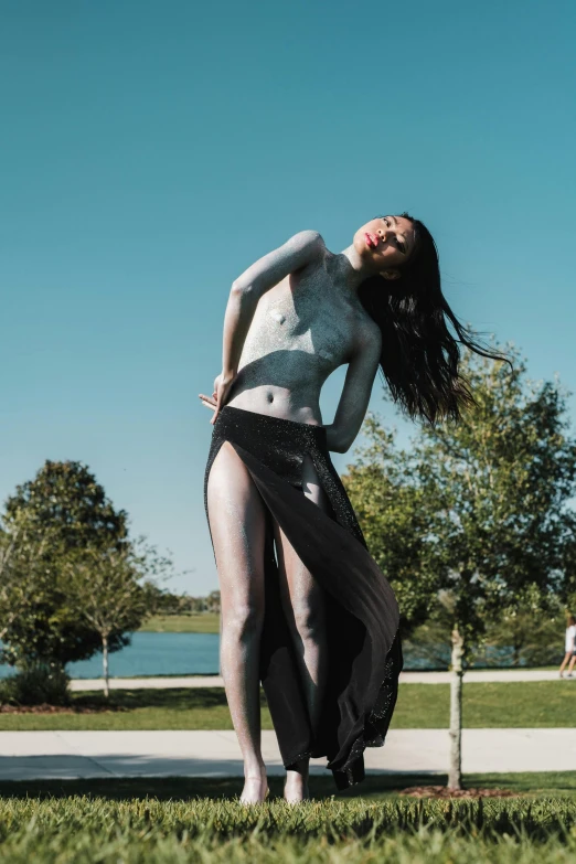 a girl in a black skirt and body paint poses for a po