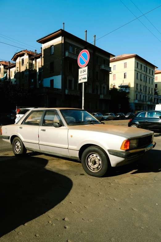 an old white car parked next to two parking meters