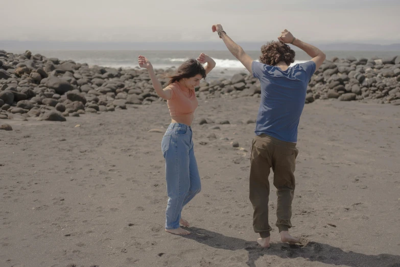 two people standing on a beach holding a kite