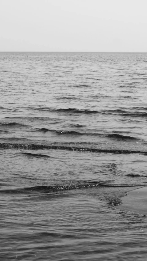 a man and woman stand near the ocean holding hands