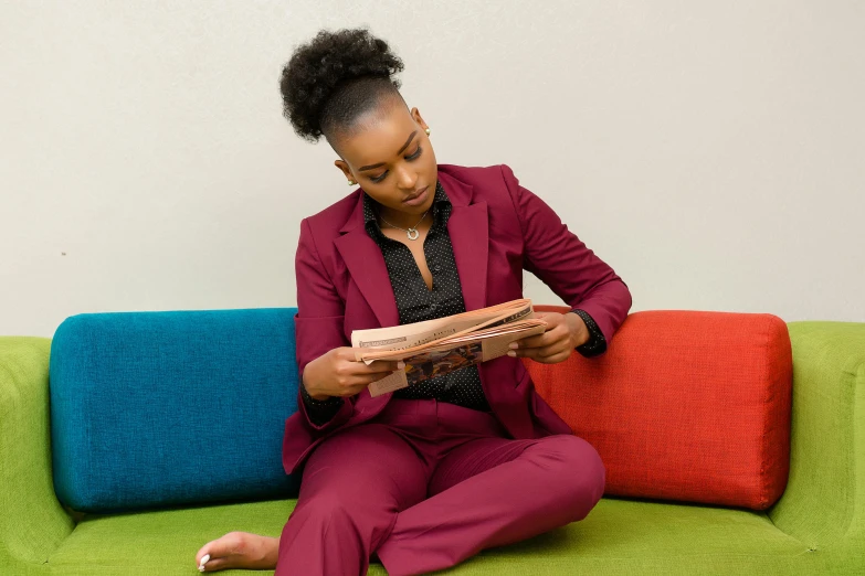 woman sitting on couch with colorful pillows and looking at magazine