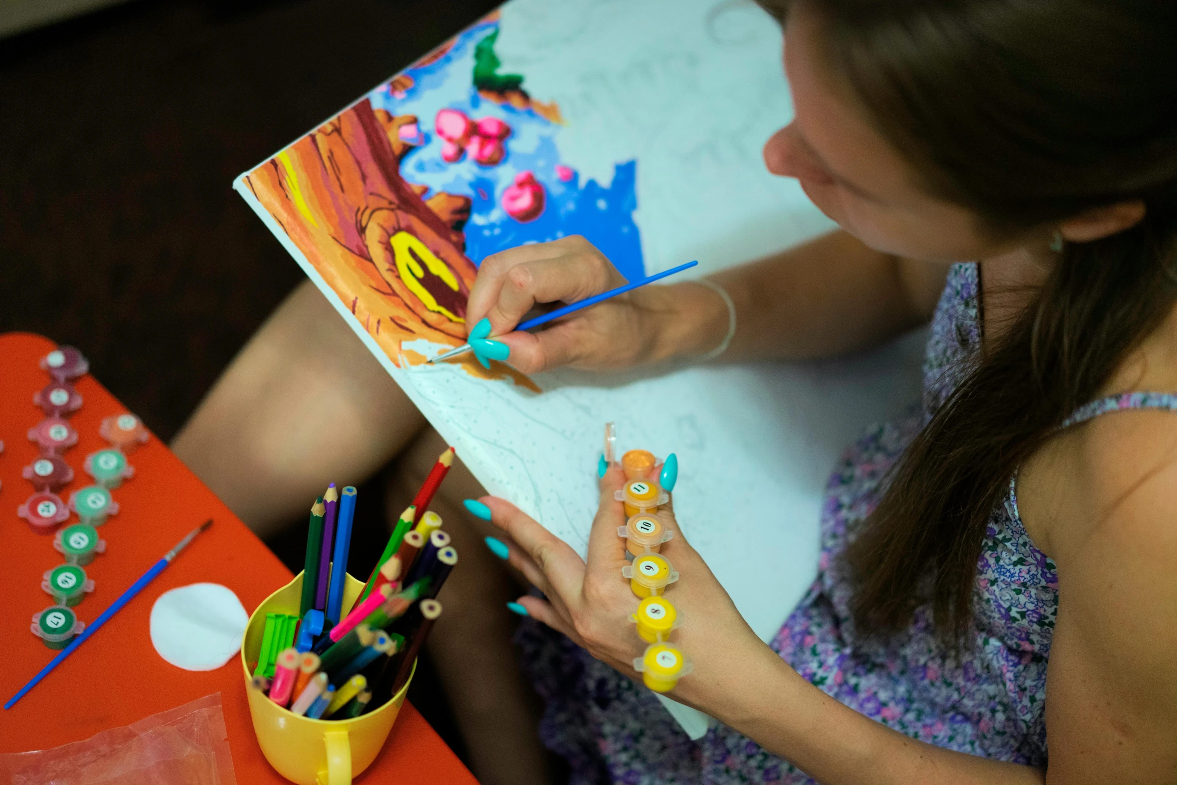 a girl using crayons to draw soing on the table