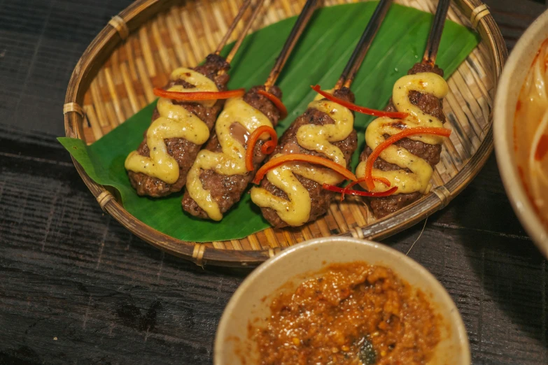 meat and vegetable skewers with sauce on a bamboo plate