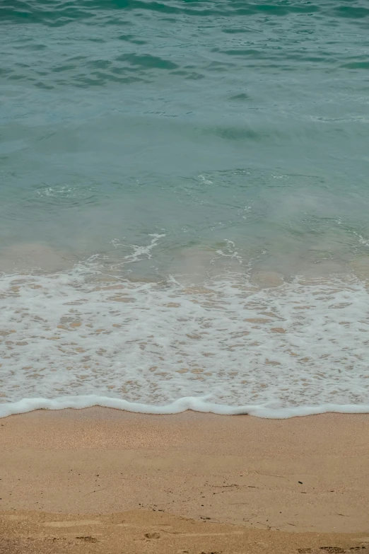 a person walking on the beach holding a surfboard