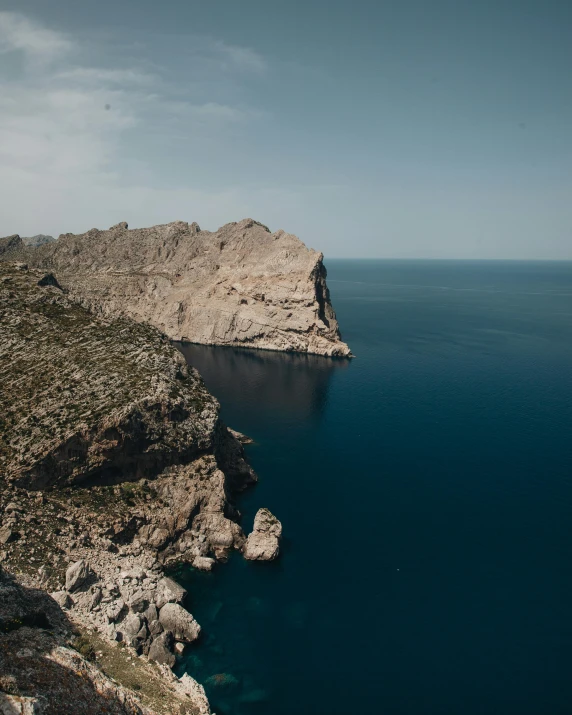 blue ocean water near a rocky hill and some rocks