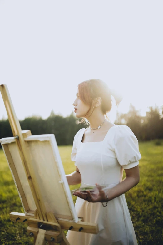 a woman in white holding an easel in her hand