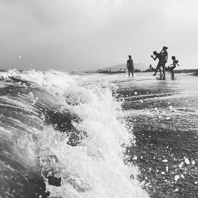 a group of people are walking along the ocean