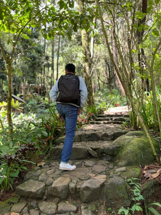 a person is wearing a backpack while walking down a trail