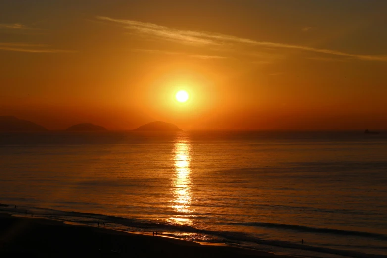 the sun sets over the water and mountains