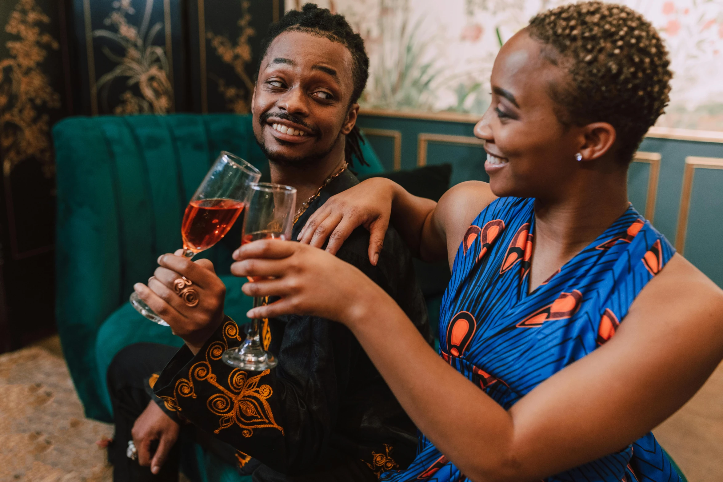 a man and woman are standing while drinking wine