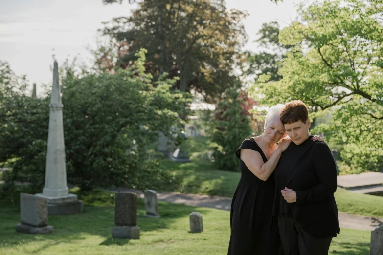 woman in black dress talking on cell phone while standing near grave