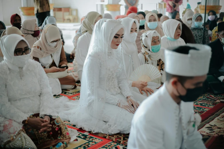 a group of people in white clothes sitting next to each other