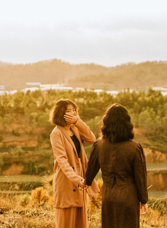 two woman in dress talking to each other in a field