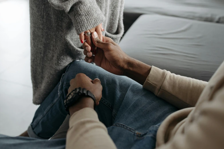 two people holding hands while sitting on a couch