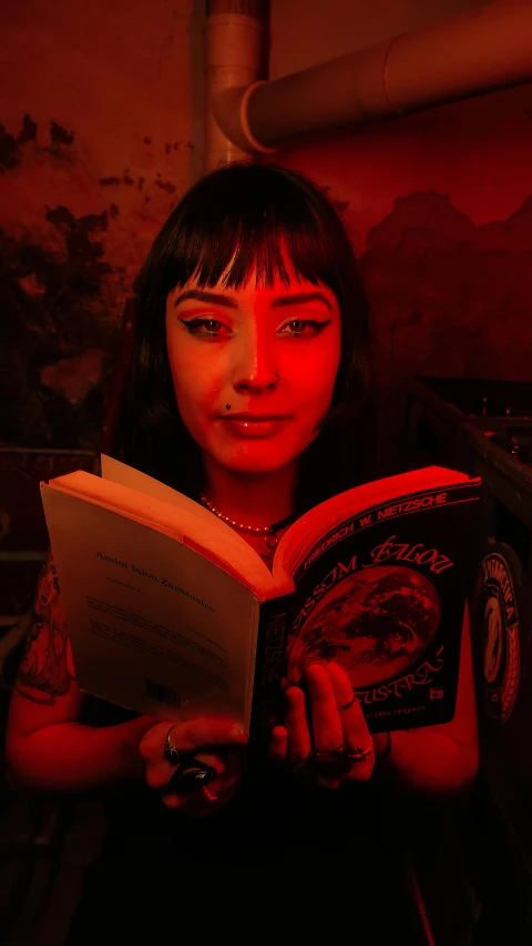 a woman holding up a book with a red light on it