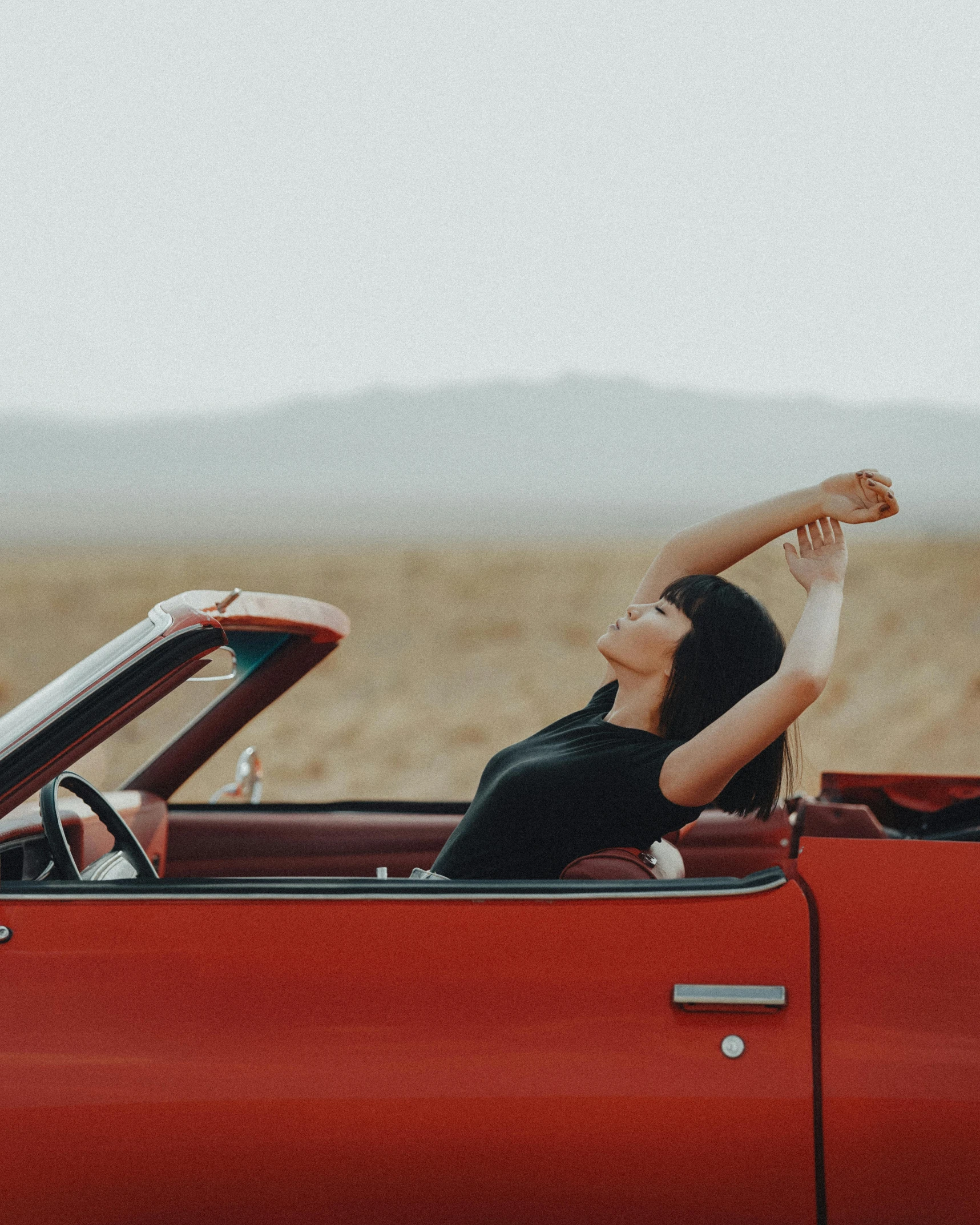 woman in black shirt sitting in red convertible car