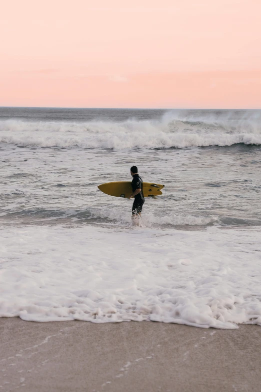 a man holding a yellow surfboard standing in front of the ocean