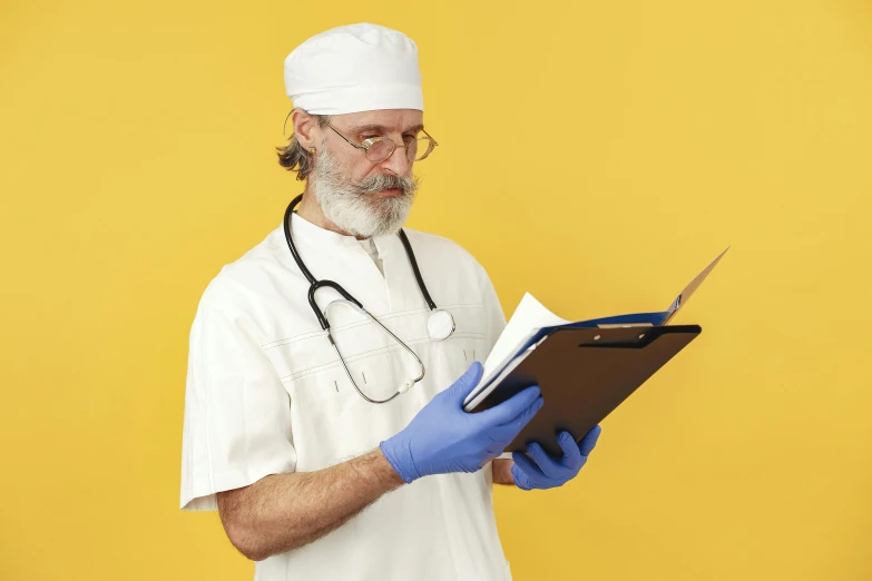 an older male nurse in white is using a clipboard