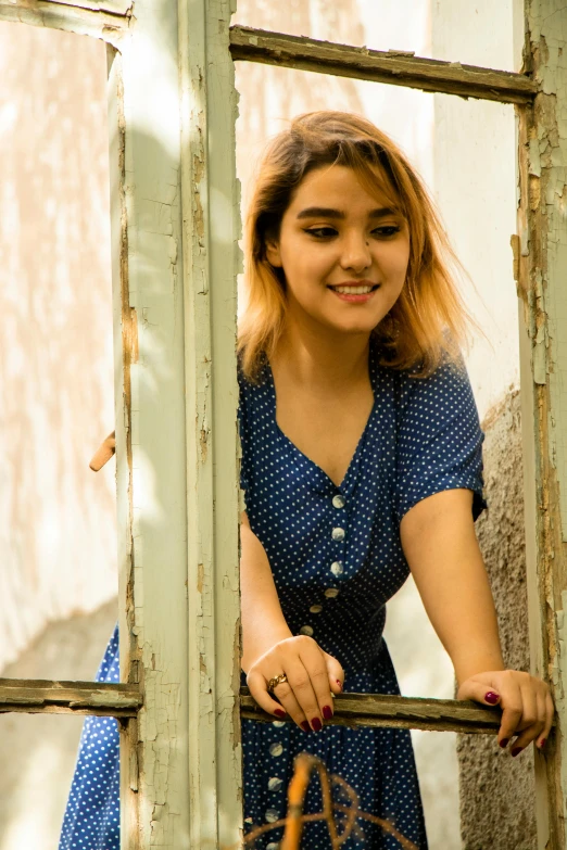 a woman poses for a picture behind a window