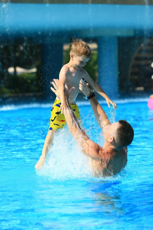 a man is playing with a child in a pool