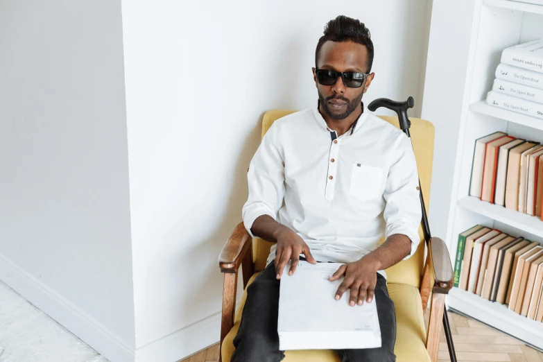 a man sitting in a chair wearing sunglasses and holding papers