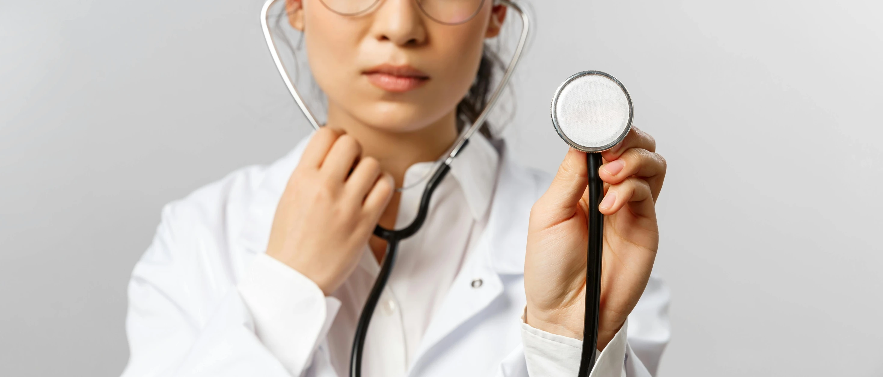 a doctor in white coat using a stethoscope to examine a patient's heart