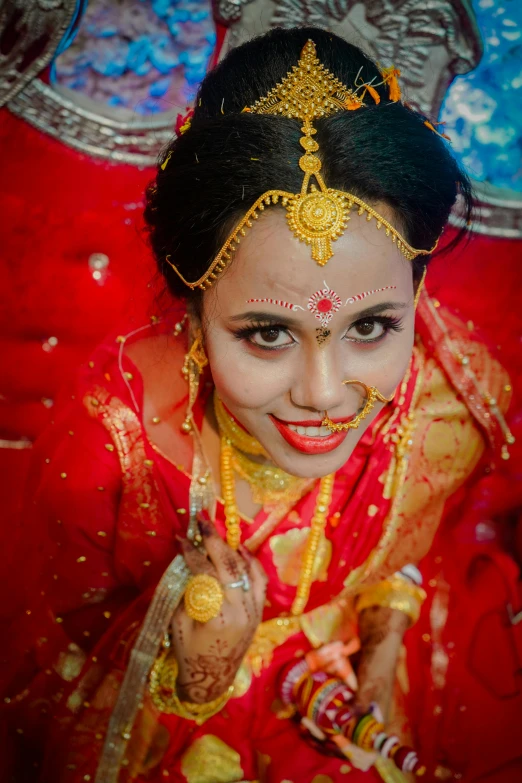 a woman in an orange and red saree with gold jewellery