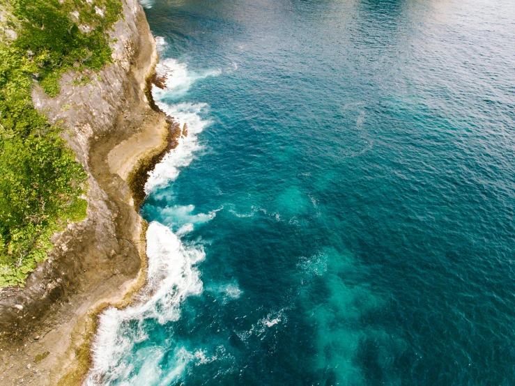 a train traveling along the side of a cliff near water