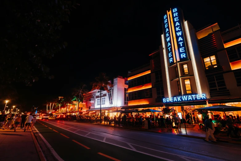 a city street at night with pedestrians and store fronts