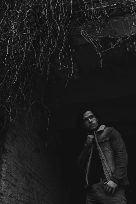 man standing in dark doorway with ivy growing on the roof