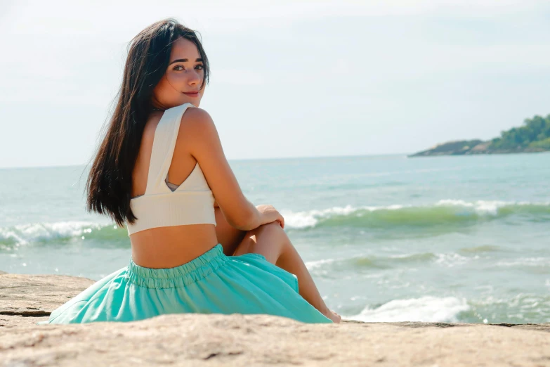 the woman is sitting on a rocky beach