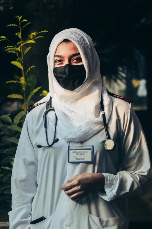 a man with a face mask and a stethoscope on standing next to some flowers