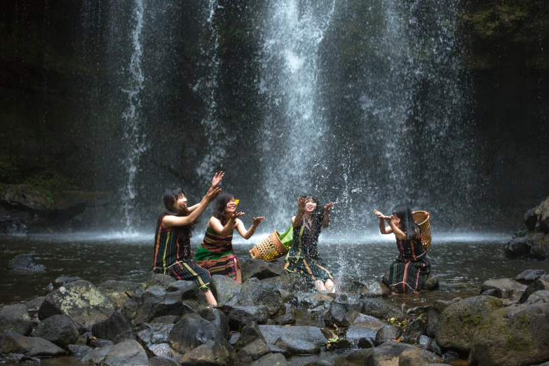 people in costume dancing next to a waterfall