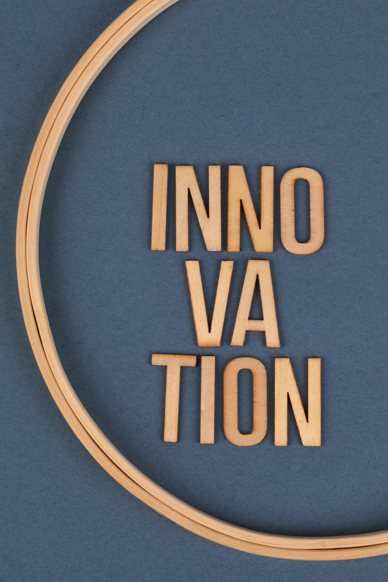 the word innovation carved into wood letters sits on a blue background