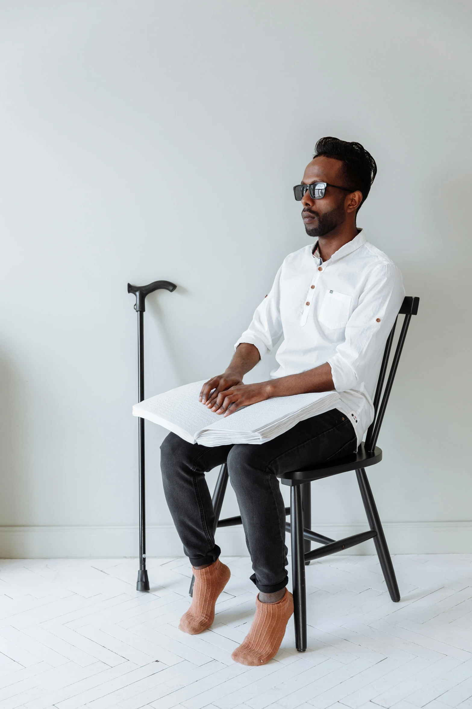 a person sits in a black chair and reads a magazine