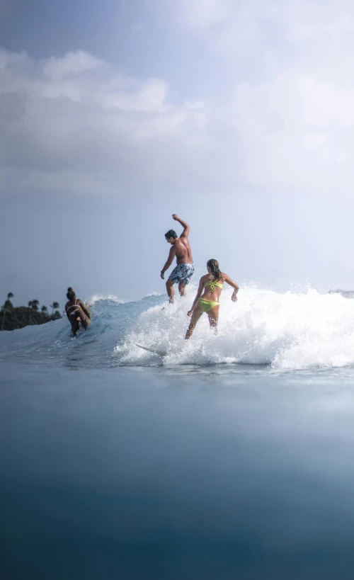 three people on surfboards riding a small wave