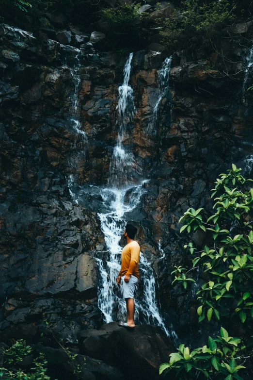 there is a man standing on a cliff overlooking a waterfall