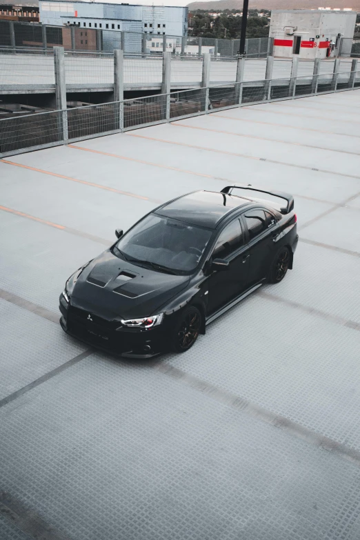 a black car parked on top of a cement parking lot