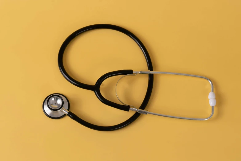 a black stethoscope sitting on top of a yellow surface