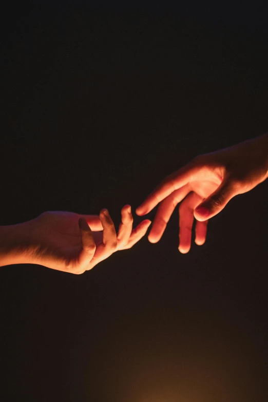 a pair of people reaching out for each other with their hands