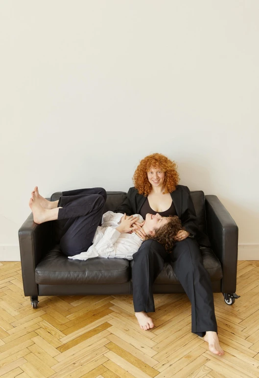 a man and a woman sit on a black couch