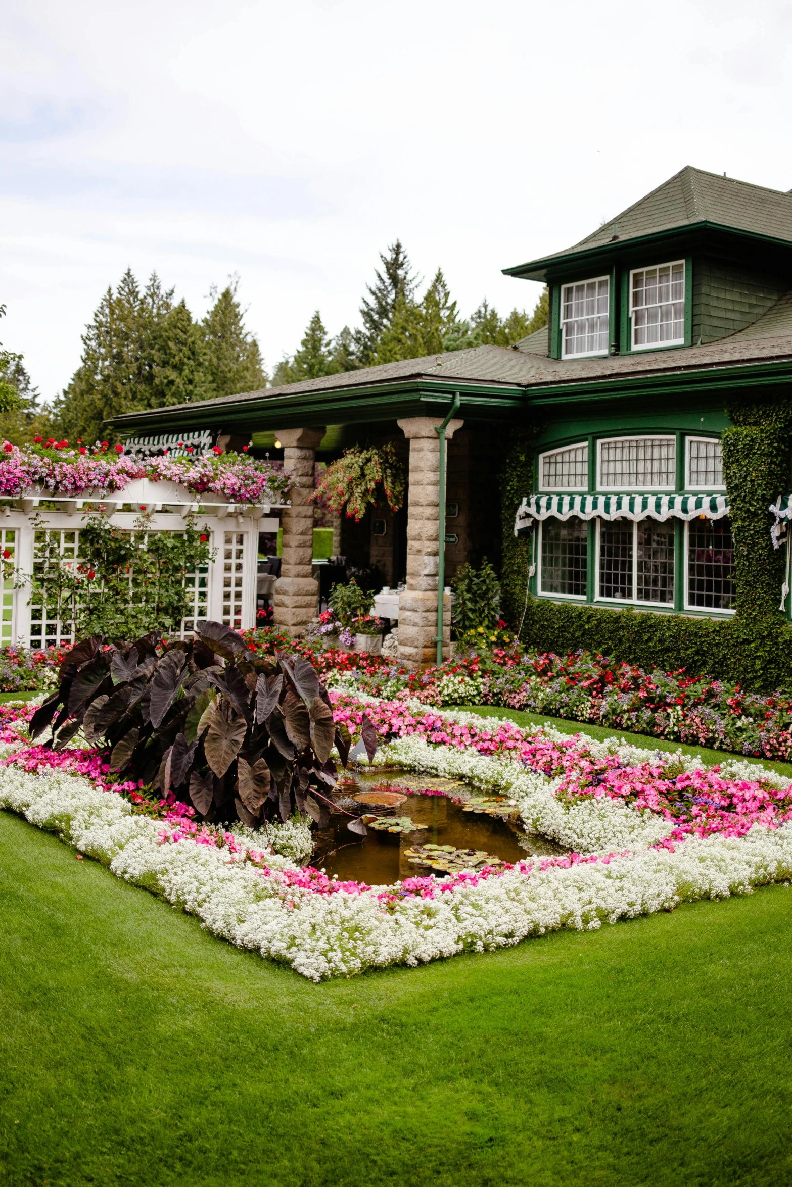 a flower garden is displayed in front of a large house