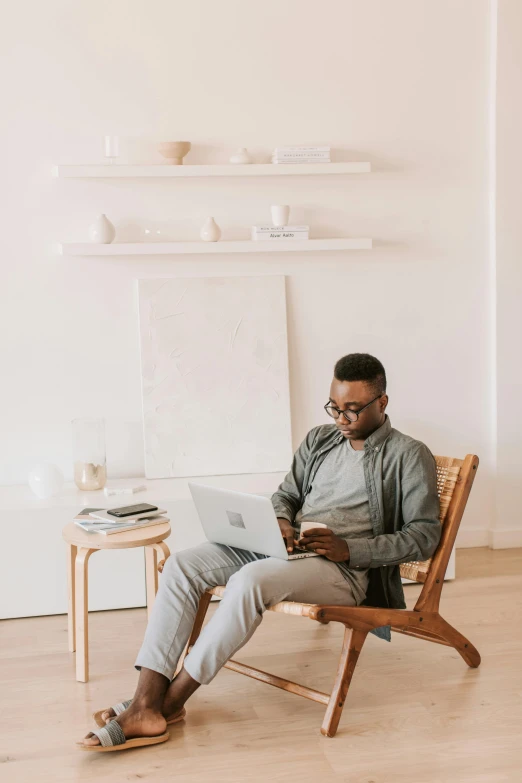 a man is sitting on a chair with a laptop