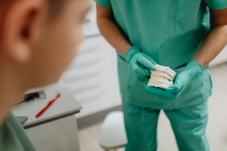 surgeon with green scrubs and gloves holding bandage in his hands