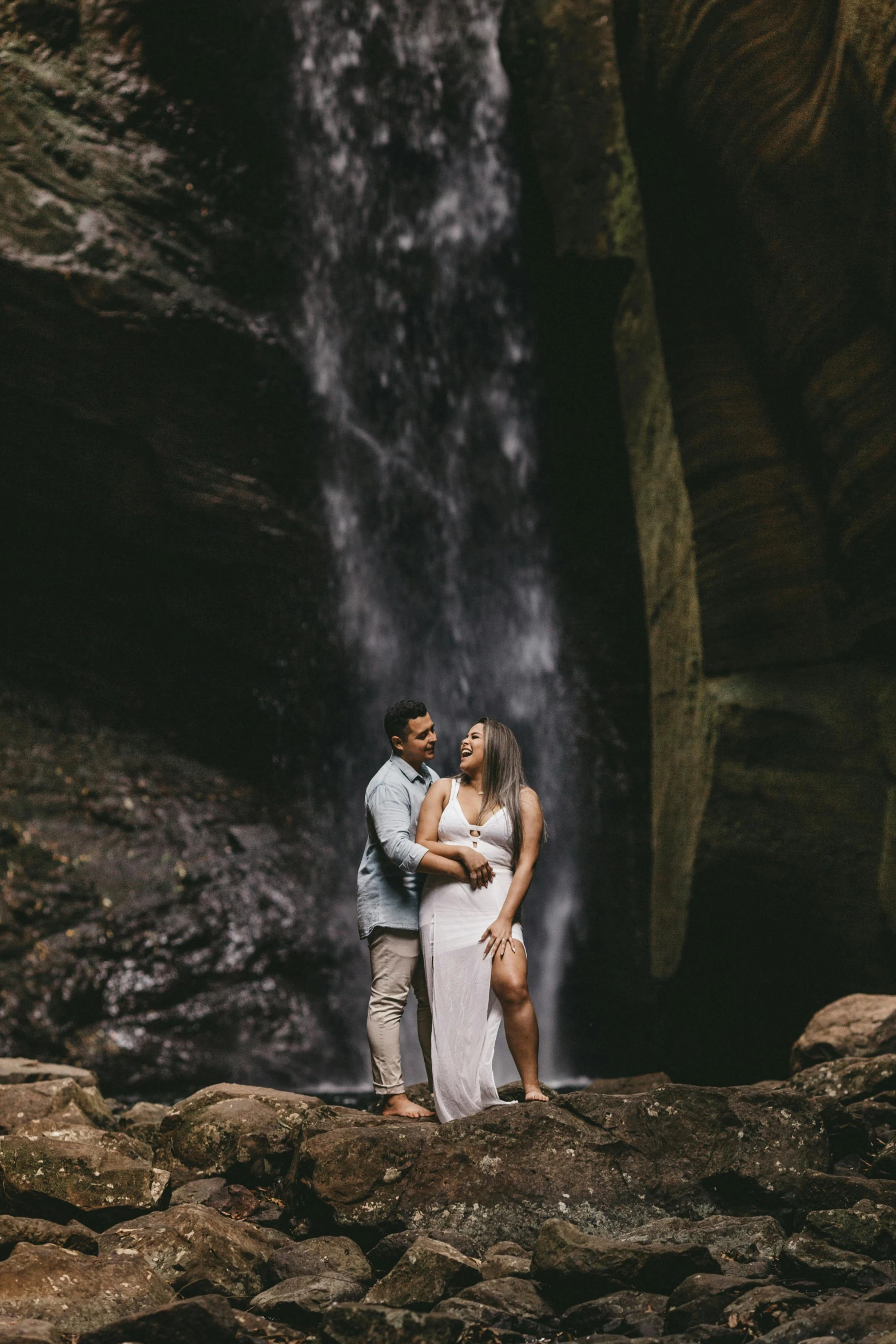 a couple stands next to a large waterfall